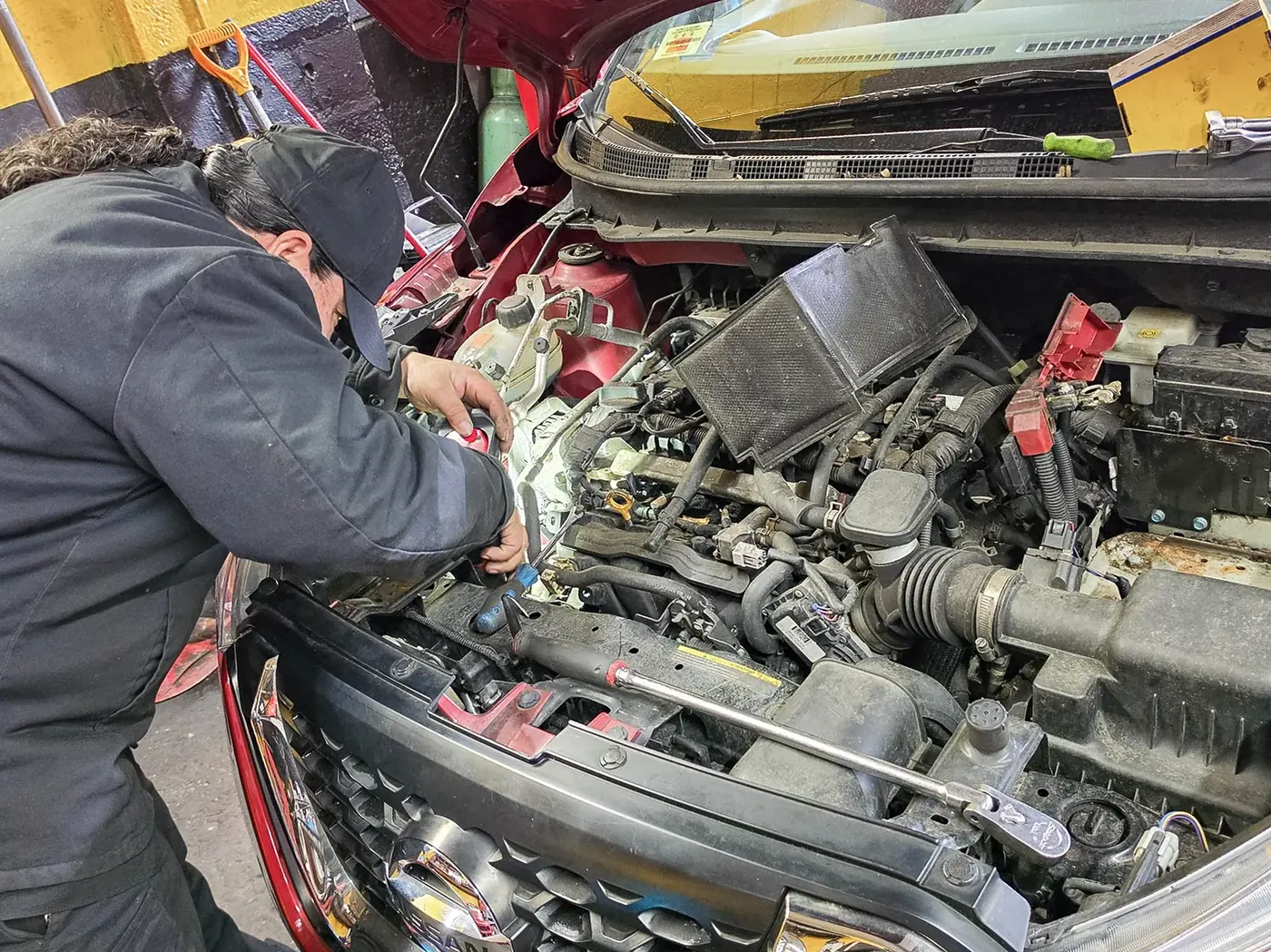 Mecánico realizando trabajo práctico bajo el capó de un vehículo