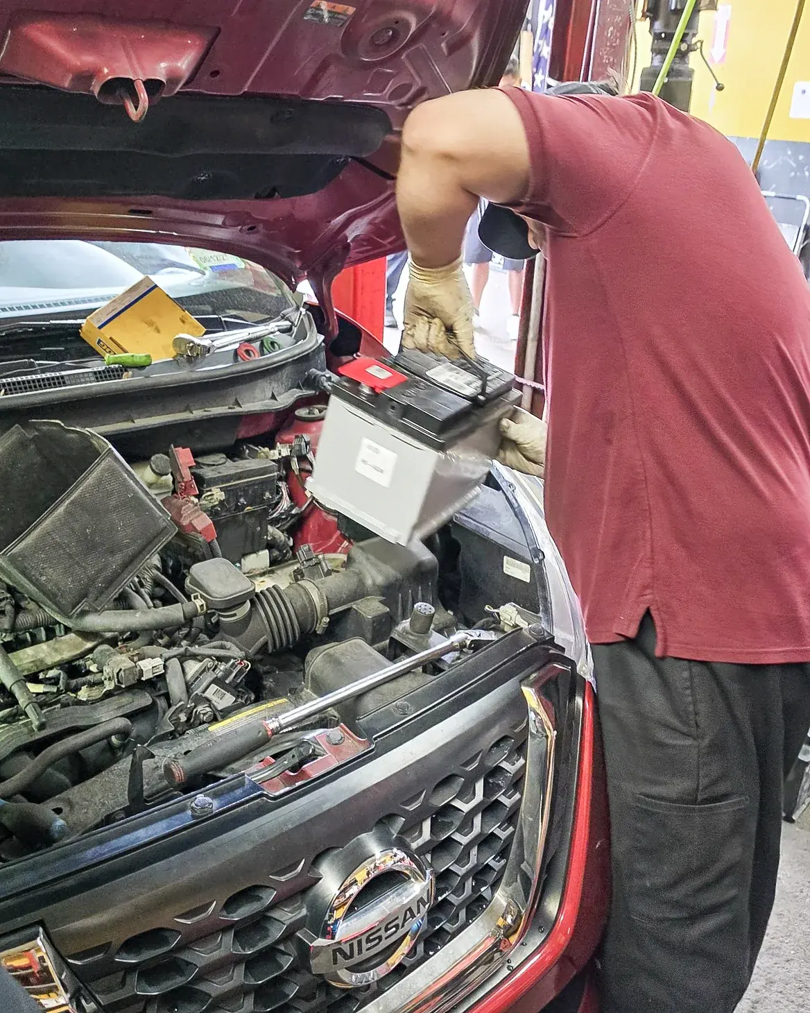Mecánico instalando una batería en un vehículo rojo