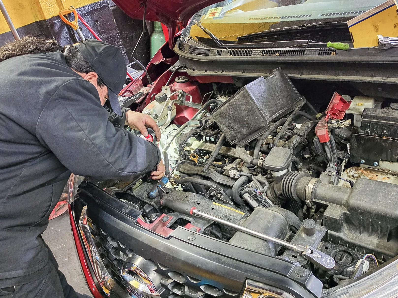 Mechanic performing hands-on work under a vehicle hood